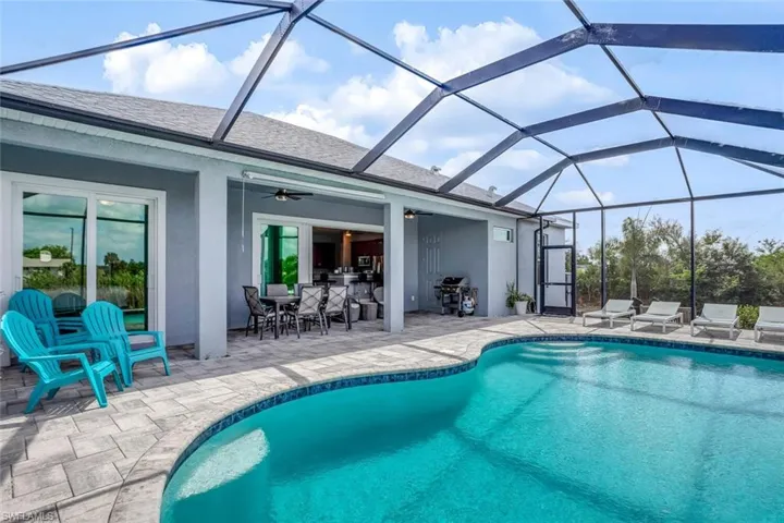 Outdoor pool featuring a sunroom, a patio, outdoor dining area, glass enclosure, and area for grilling