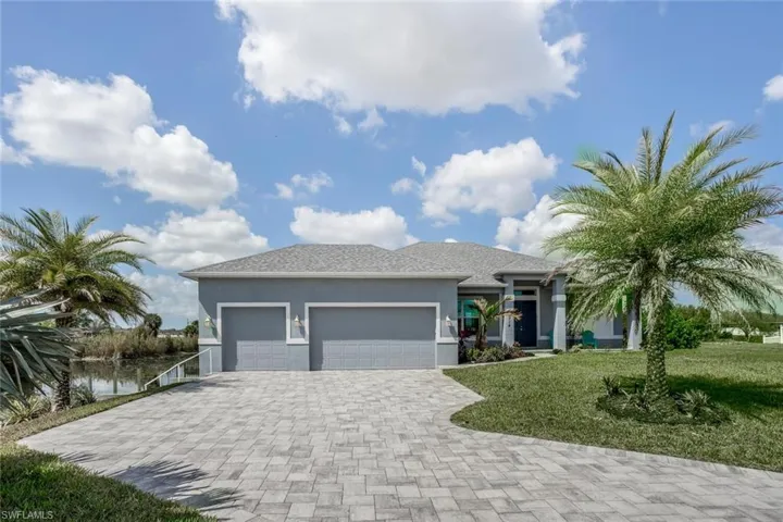 View of front of house with a front lawn, stucco siding, an attached garage, and decorative driveway