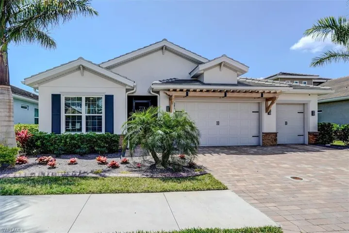 View of front of house featuring a garage, stucco siding, a tiled roof, and decorative driveway