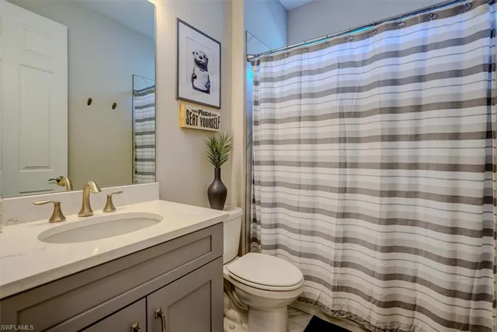 Bathroom with toilet, vanity, and a shower with curtain