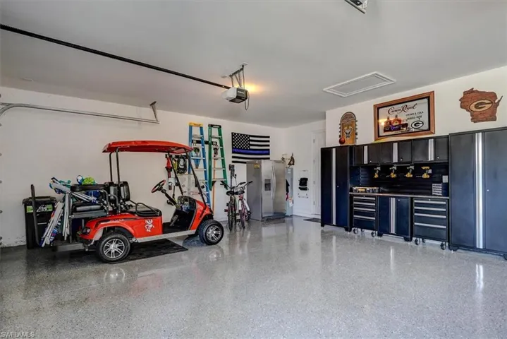 Garage with stainless steel fridge and a garage door opener
