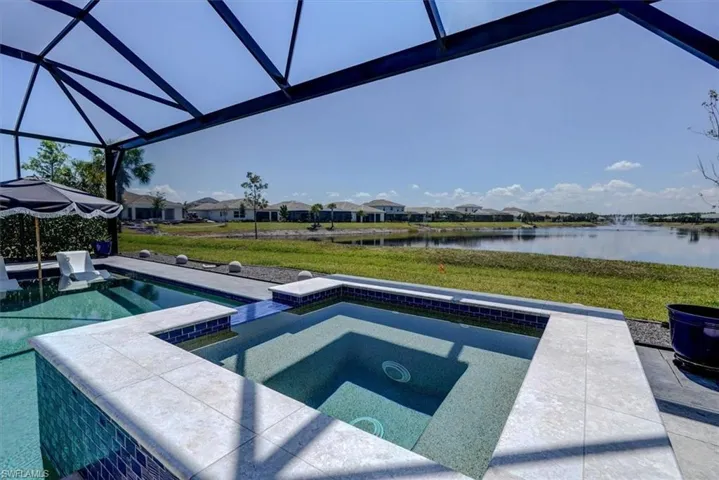 Pool featuring a yard, an in ground hot tub, glass enclosure, and a water view