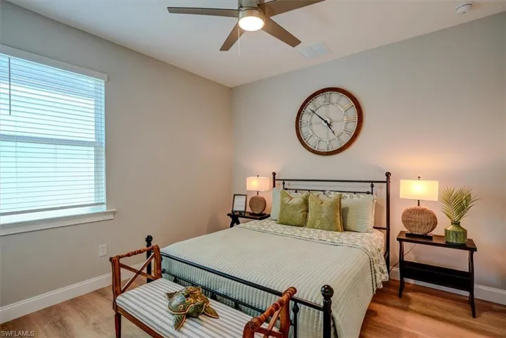 Bedroom with light wood-type flooring, visible vents, baseboards, and a ceiling fan