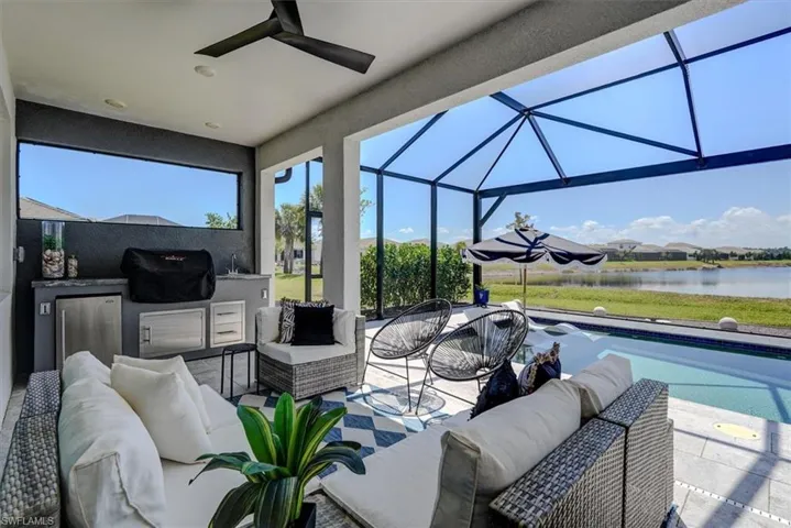 View of patio with a lanai, a water view, outdoor lounge area, an outdoor pool, and an outdoor kitchen