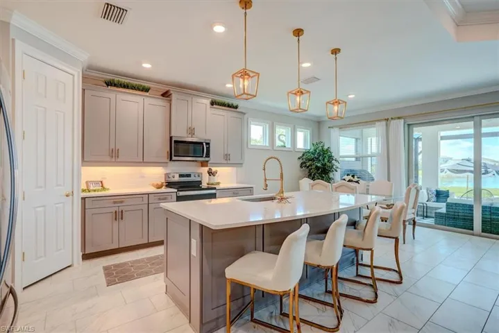Kitchen with visible vents, a sink, a kitchen breakfast bar, gray cabinetry, and stainless steel appliances