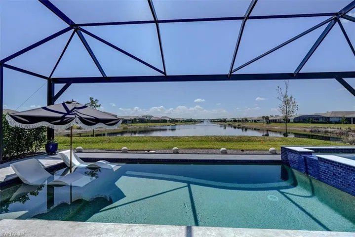 View of pool with a patio, a pool with connected hot tub, glass enclosure, and a water view