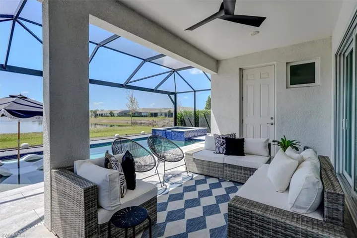 View of patio featuring an outdoor living space, ceiling fan, a pool with connected hot tub, and a lanai