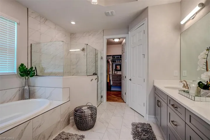 Bathroom with a garden tub, vanity, a healthy amount of sunlight, marble finish floor, and a stall shower