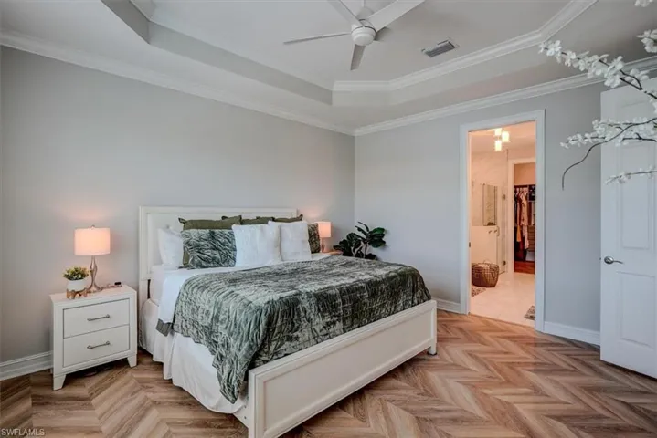 Bedroom with a raised ceiling, crown molding, baseboards, and visible vents