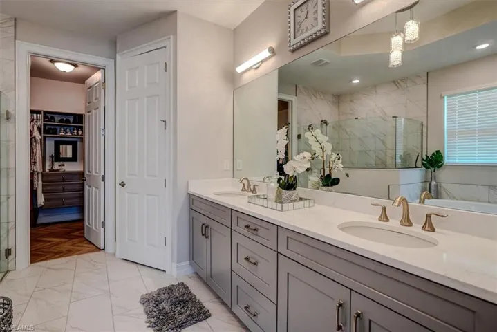 Bathroom with a shower stall, marble finish floor, and a sink
