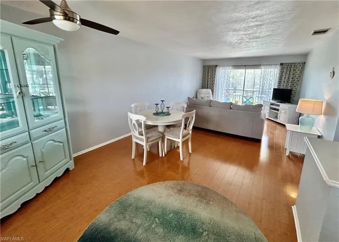 Dining space with wood finished floors, a ceiling fan, and a textured ceiling