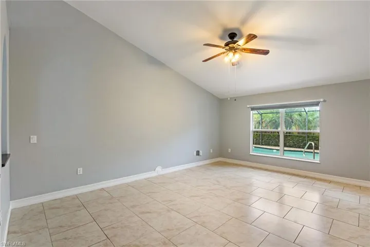 Spare room with lofted ceiling, light tile patterned floors, and a ceiling fan