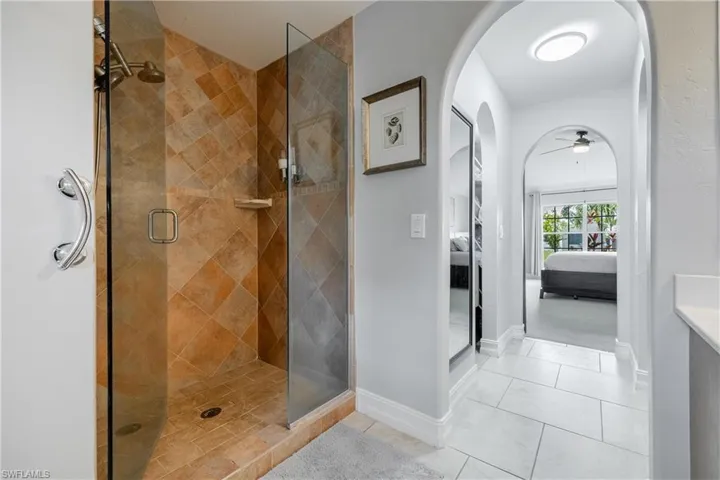 Bathroom featuring connected bathroom, a shower stall, ceiling fan, and light tile patterned floors