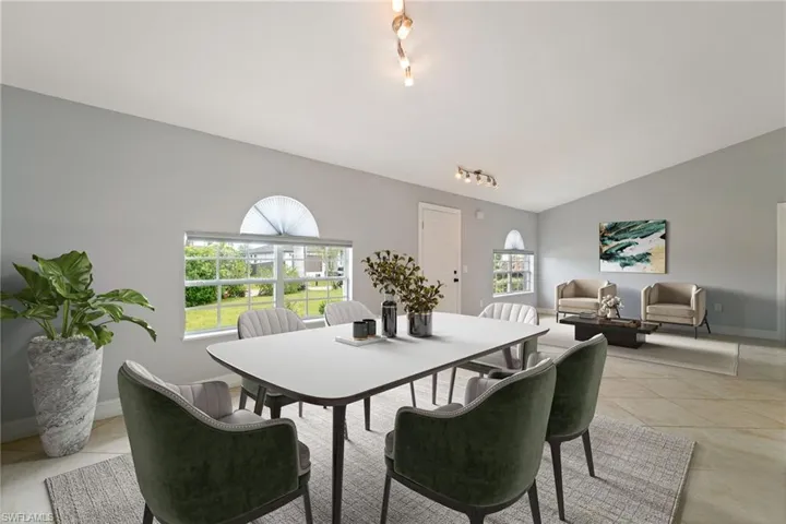 Dining room with vaulted ceiling, light tile patterned floors, track lighting, and healthy amount of natural light