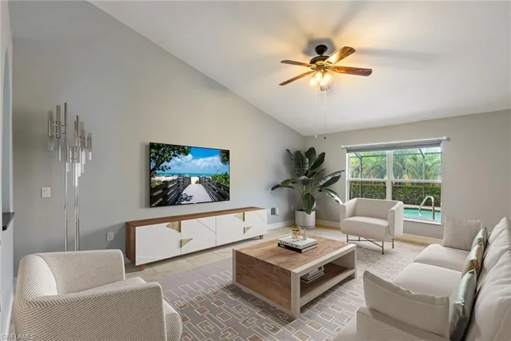 Living room with lofted ceiling, ceiling fan, and tile patterned flooring