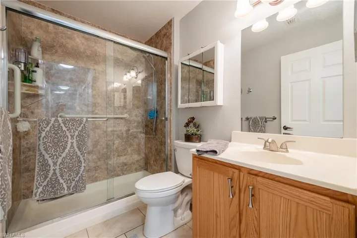 Full bath featuring light tile patterned floors, vanity, and a stall shower