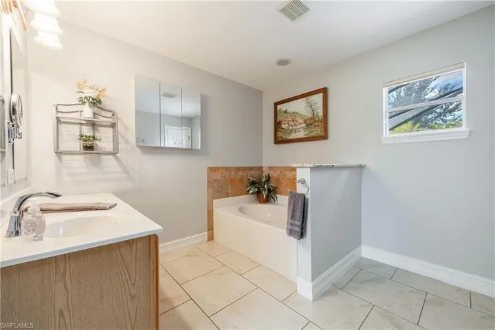 Bathroom featuring a garden tub, double vanity, and light tile patterned floors