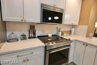Kitchen featuring white cabinetry, backsplash, and appliances with stainless steel finishes