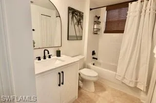 Full bathroom featuring vanity, shower / bath combo with shower curtain, tile patterned flooring, and toilet