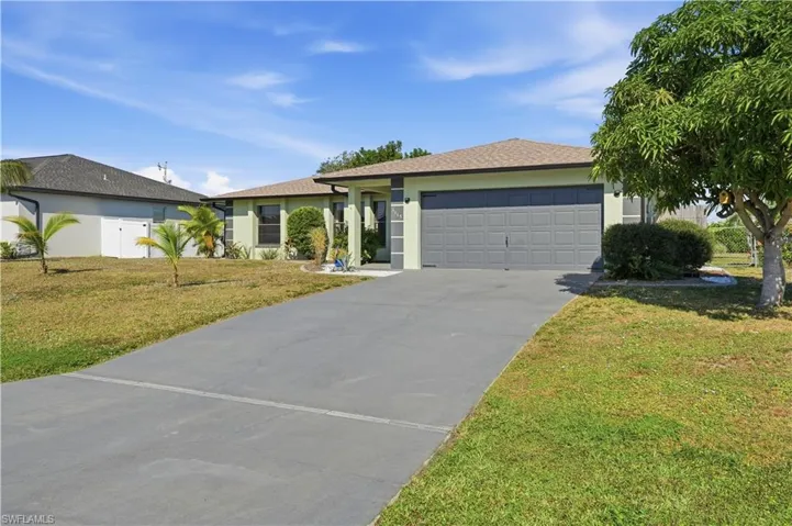 Single story home with a front yard, stucco siding, concrete driveway, and a garage