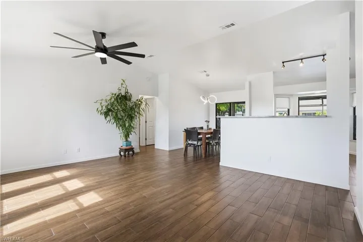 Living area with vaulted ceiling, wood tiled floors, ceiling fan, and a chandelier