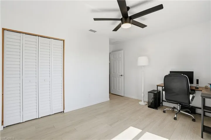 Office area with light wood-style floors and a ceiling fan