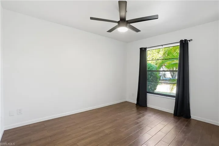 Spare room with dark wood-style floors and a ceiling fan