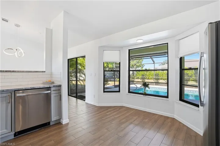 Kitchen featuring light stone counters, dishwasher, freestanding refrigerator, decorative light fixtures, and wood tiled floors