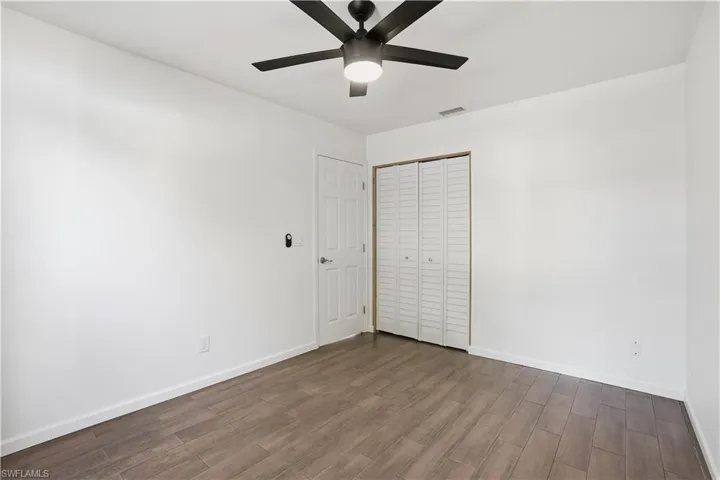 Unfurnished bedroom featuring dark wood finished floors, a closet, and a ceiling fan