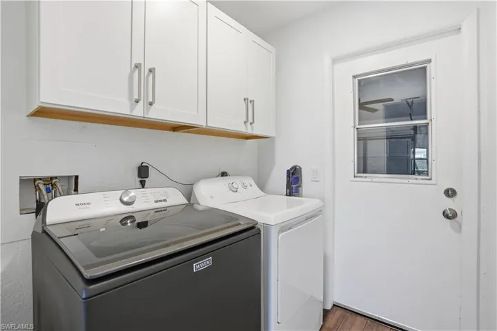 Laundry room with cabinet space, washing machine and dryer, and dark wood-style flooring