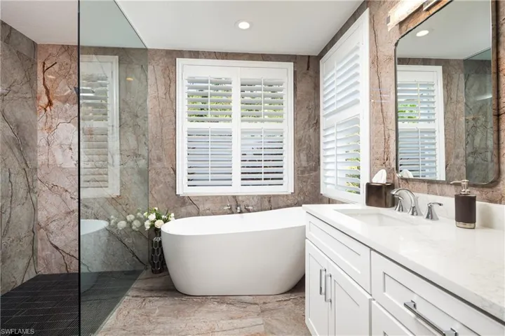 Bathroom featuring tile walls, tile floors, large vanity, and plenty of natural light