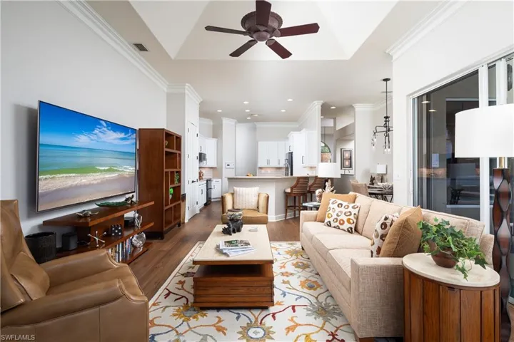 Living room with ceiling fan, hardwood / wood-style flooring, and ornamental molding