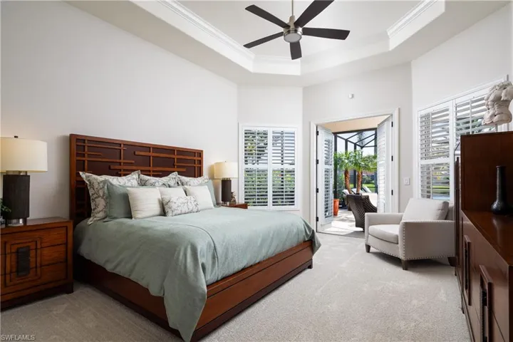 Carpeted bedroom with a towering ceiling, access to outside, ceiling fan, a tray ceiling, and crown molding