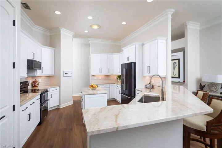 Kitchen with light stone counters, a center island, tasteful backsplash, and black appliances