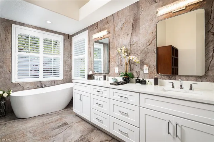 Bathroom featuring tile walls, tile floors, a bathtub, and double sink vanity