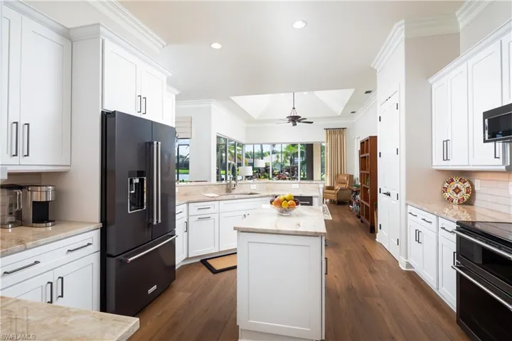 Kitchen with a center island, dark wood-type flooring, a tray ceiling, high end black refrigerator, and ceiling fan