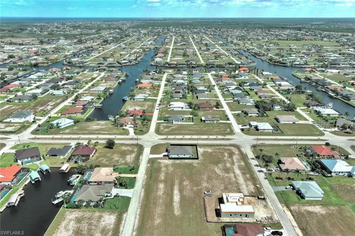 Aerial view of property and surrounding area featuring a nearby body of water and nearby suburban area