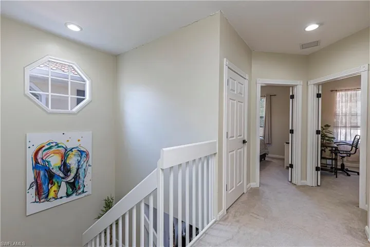 Corridor with plenty of natural light, an upstairs landing, light colored carpet, and recessed lighting
