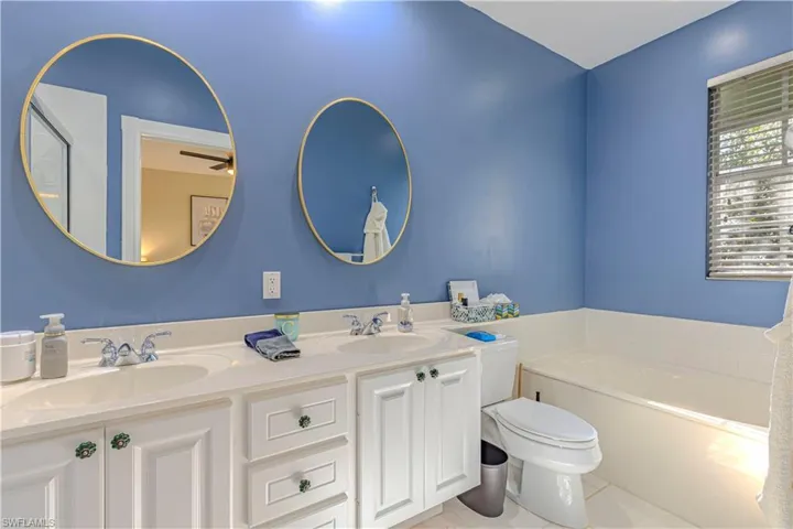 Bathroom featuring a garden tub, double vanity, and light tile patterned flooring