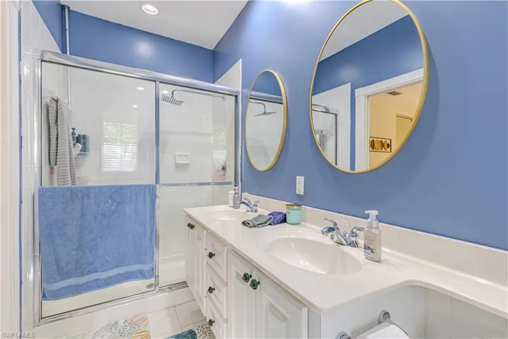 Full bathroom with double vanity, a shower stall, and light tile patterned flooring