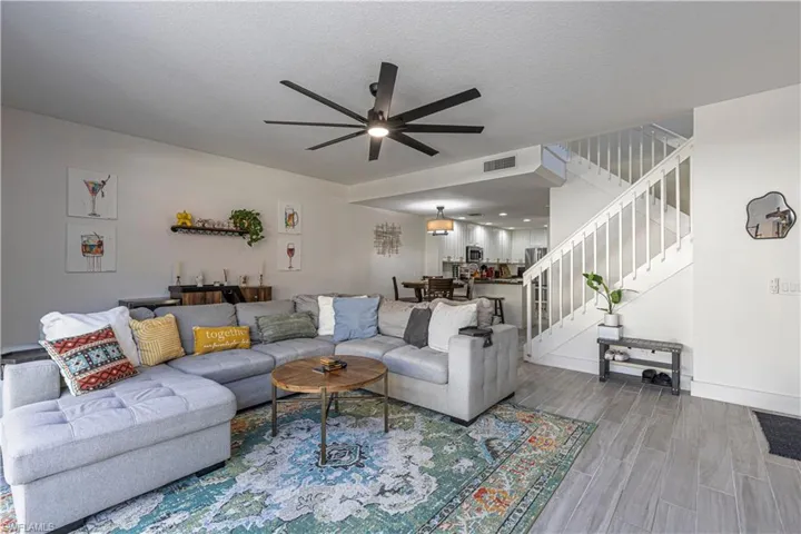Living area with ceiling fan, wood finish floors, and a textured ceiling