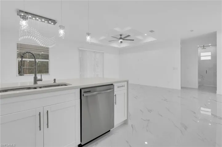 Kitchen featuring light stone countertops, dishwasher, light marble finish flooring, white cabinets, and coffered ceiling