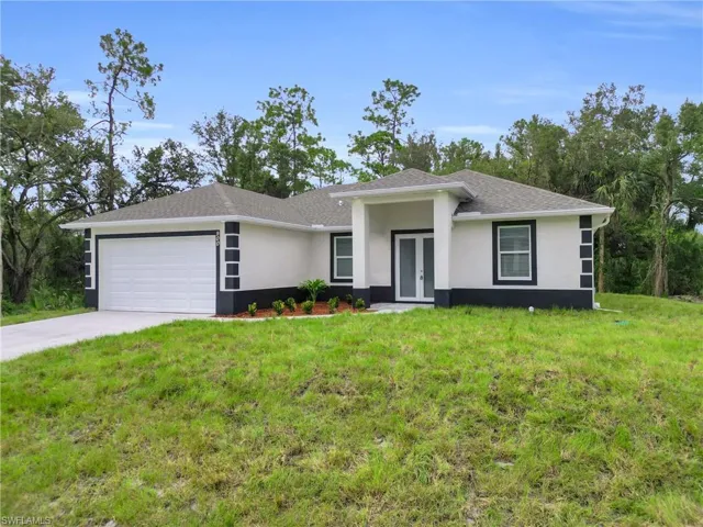View of front facade featuring a front lawn, an attached garage, and concrete driveway