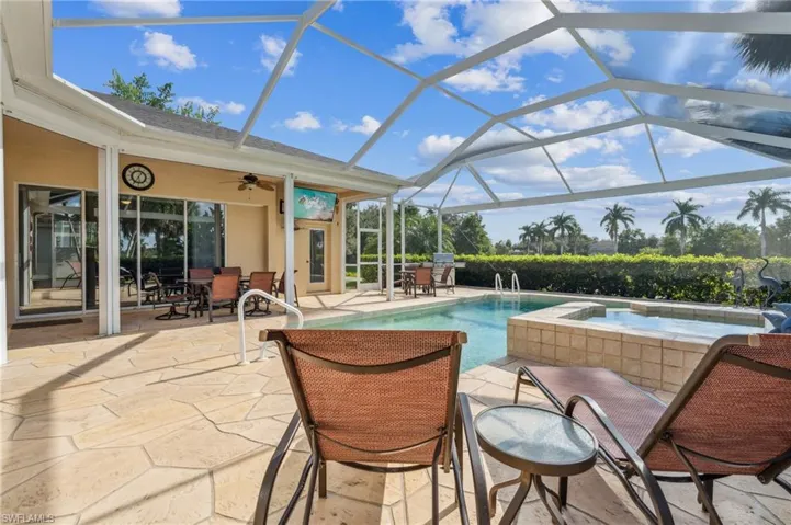 View of swimming pool with a patio, glass enclosure, ceiling fan, and an in ground hot tub