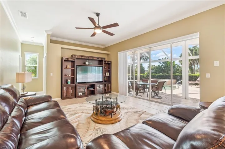 Living room with ceiling fan, light tile patterned flooring, and a healthy amount of sunlight