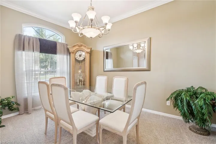 Carpeted dining space featuring a chandelier and crown molding