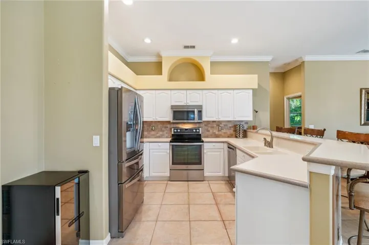 Kitchen with a kitchen bar, white cabinetry, stainless steel appliances, and kitchen peninsula