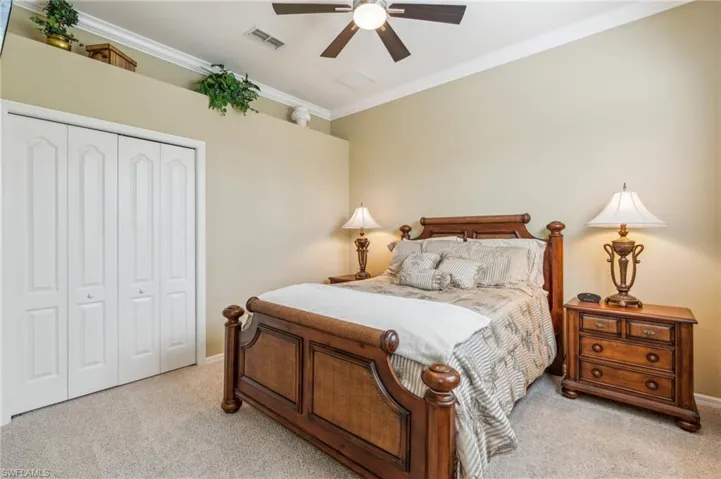 Bedroom featuring crown molding, light carpet, ceiling fan, and a closet