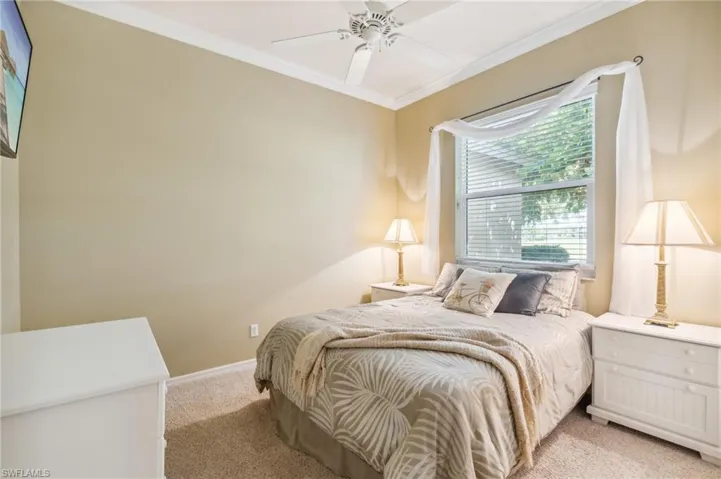 Bedroom with ceiling fan, light carpet, and crown molding