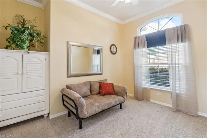 Sitting room featuring ceiling fan, light carpet, and crown molding